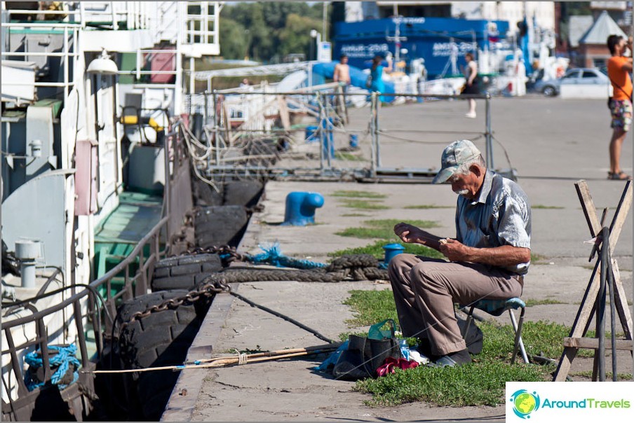 Fisherman in a silver shirt on the pier of Azov