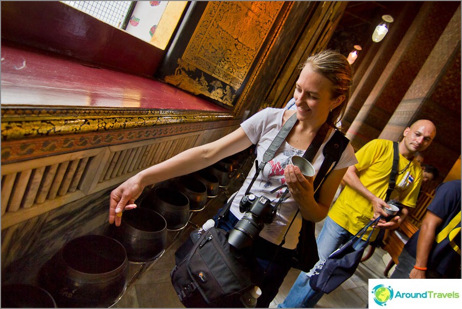 We throw coins for luck in the temple of the Reclining Buddha We throw coins for luck in the temple of the Reclining Buddha